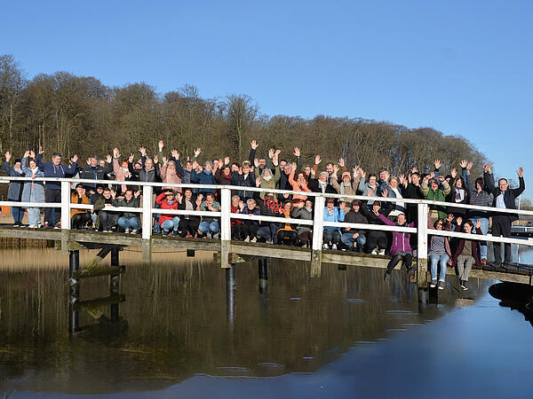 Teamfoto (rund 50 Personen) der Brücke Flensburg auf einer Brücke bei Sonnenschein